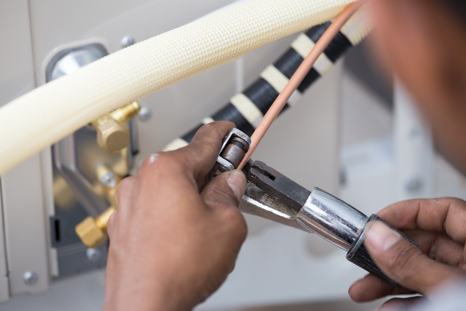 worker cutting copper pipe of air conditioner